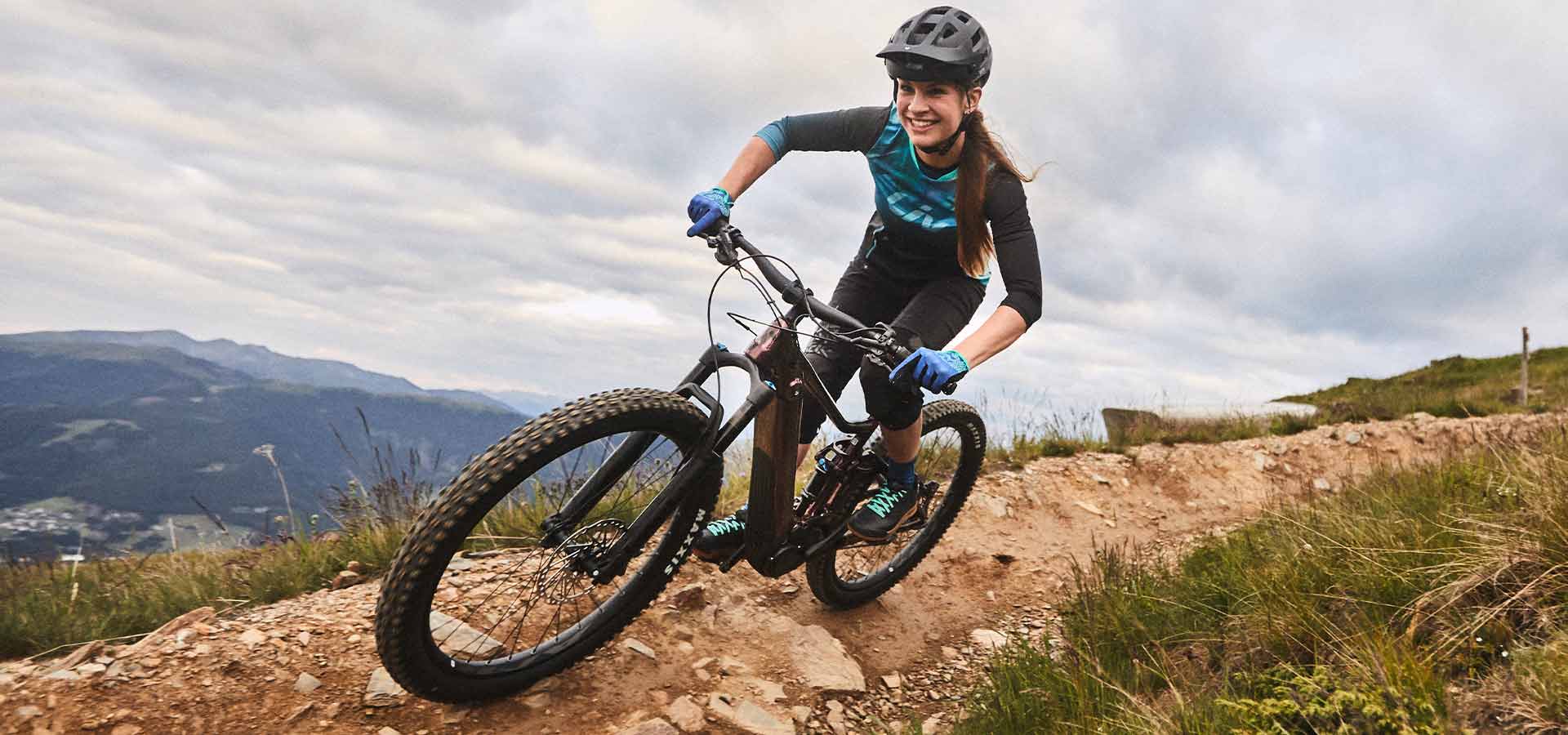 Purchase advise on the perfect e-bike.
A woman riding an e-bike on the mountain top.